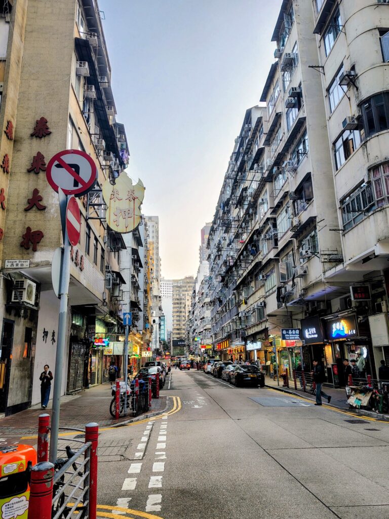 The busy, vertical urban landscape of Saigon Street in Hong Kong, captured for a travel blog detailing the experiences of a trans man navigating major Asian cities.